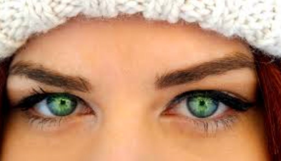 headshot of a woman wearing a winter cap with healthy green eyes